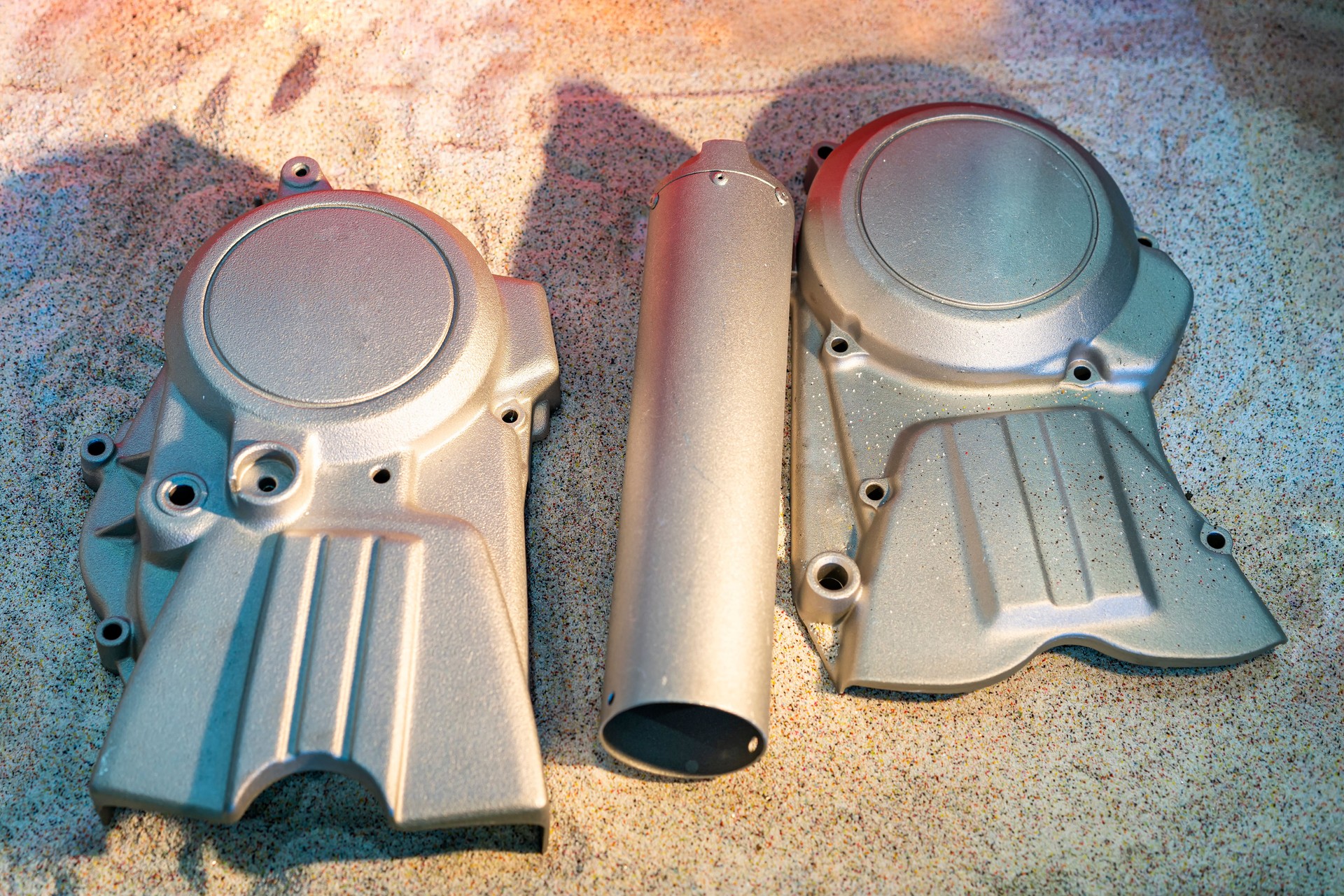 Cover crankcase aluminum casting product of motorcycle and other automotive pats show after cleaning by shot blasting process and put it on sand in box